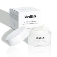 Barattolo di crema Medik8 C-Tetra e la sua confezione in cartone bianco esposti su uno sfondo bianco pulito con ombre morbide. Il barattolo aperto in vetro satinato bianco presenta il logo Medik8 ed è etichettato come C-TETRA CREAM Lipid Vitamin C Radiance Cream da 50 mL.