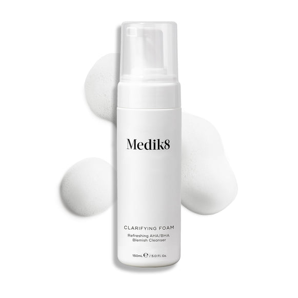 Flacone con erogatore di Medik8 Clarifying Foam esposto su uno sfondo bianco pulito con tre ciuffi di schiuma bianca e leggera. Il testo lo identifica come Refreshing AHA/BHA Blemish Cleanser da 150 mL.-22
