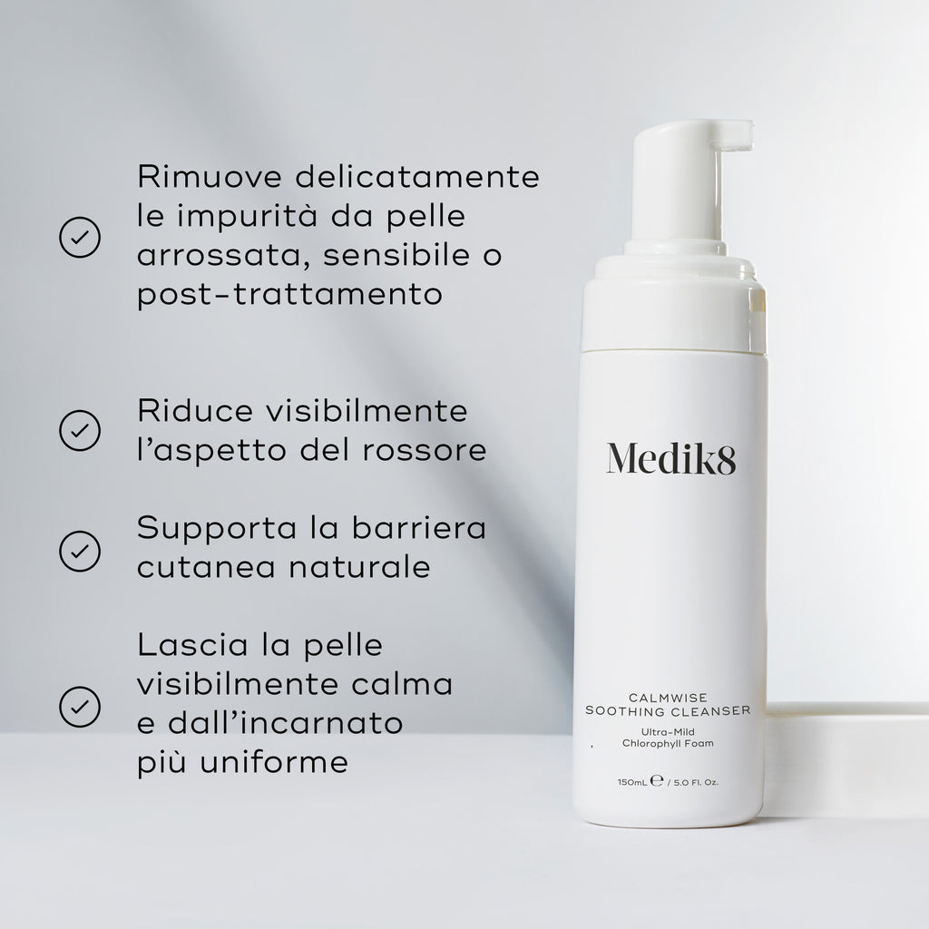 Il flacone di Medik8 Calmwise Soothing Cleanser si trova su un blocco bianco contro uno sfondo grigio chiaro. Il testo in italiano descrive i benefici della schiuma ultra-delicata alla clorofilla, tra cui la rimozione delicata delle impurità dalla pelle arrossata, sensibile o post-trattamento, la riduzione visibile dell'aspetto del rossore, il supporto alla barriera cutanea naturale e il lasciare la pelle visibilmente calma con un incarnato più uniforme.