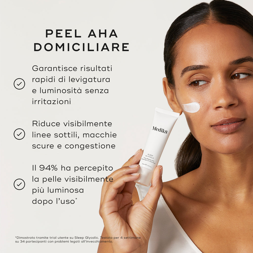 Primo piano di una modella che applica Medik8 Sleep Glycolic sulla guancia su uno sfondo chiaro. Il testo in italiano descrive in dettaglio i vantaggi del peel AHA domiciliare: garantisce risultati rapidi di levigatura e luminosità senza irritazioni, riduce visibilmente linee sottili, macchie scure e congestione, e il 94% ha percepito la pelle visibilmente più luminosa dopo l'uso.